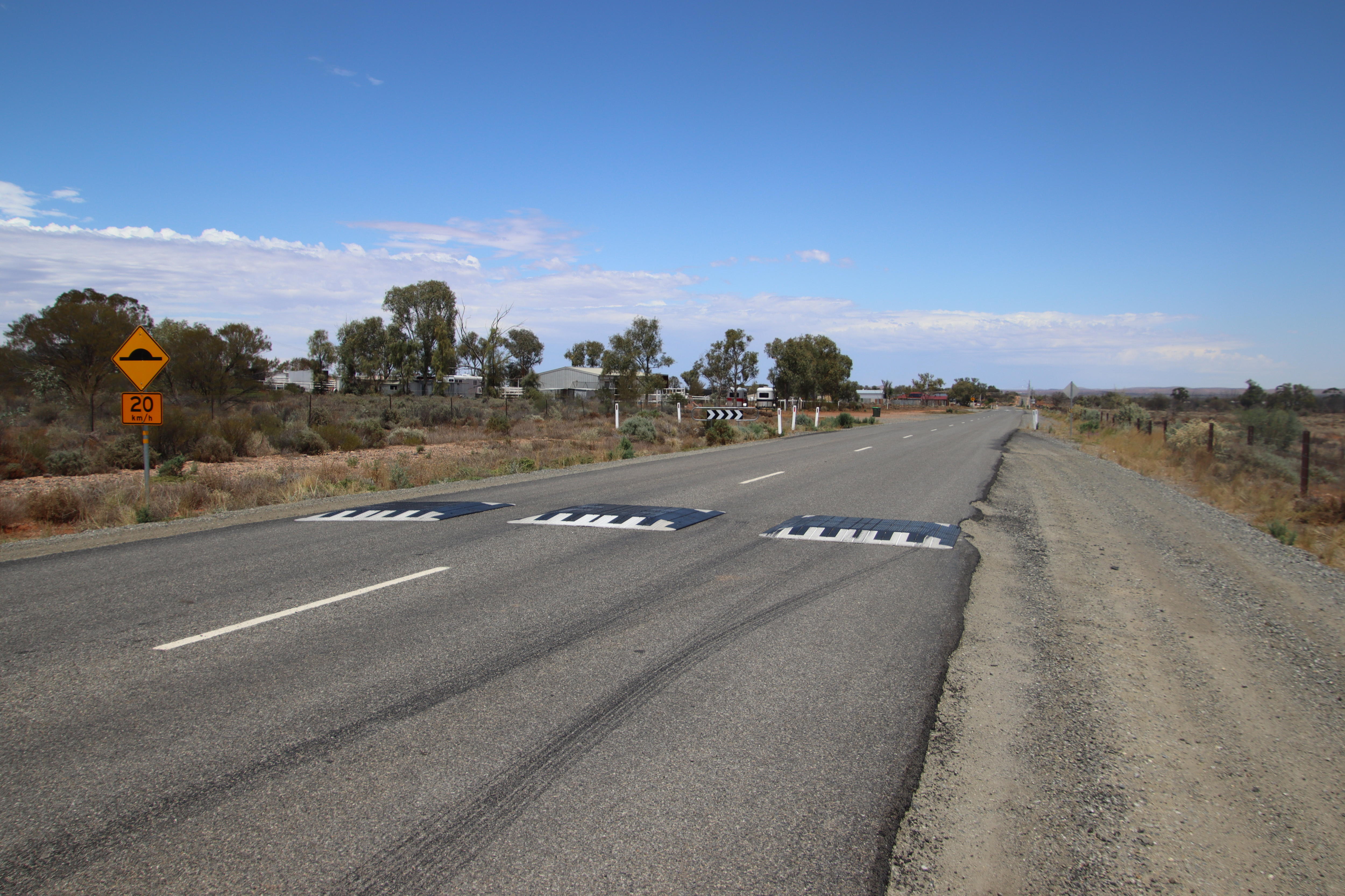 A road with three speed bumps. 