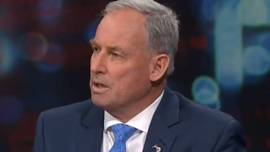 A man in a dark suit and blue tie with grey hair appears on Q+A.