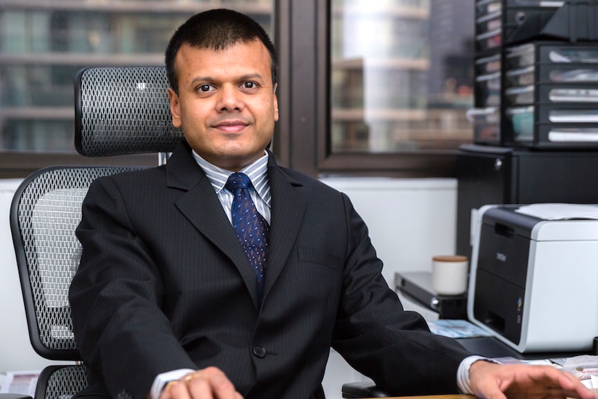 a man sitting behind a desk and looking forward