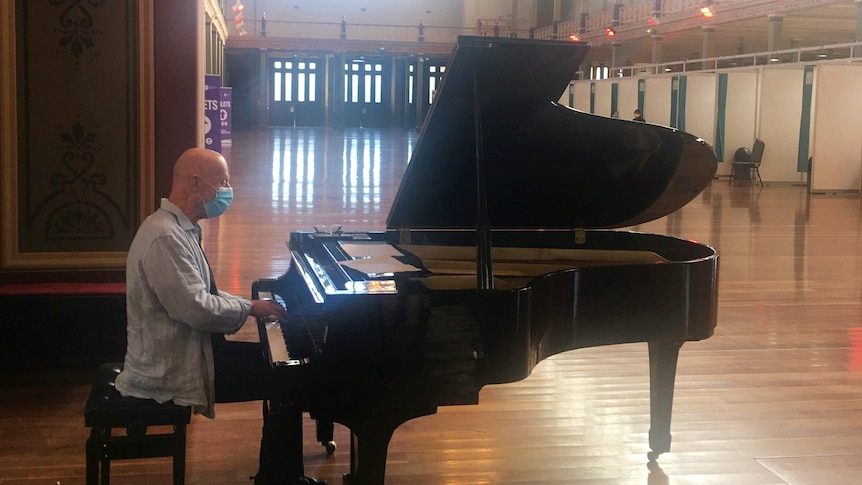 A man playing a grand piano inside the Melbourne Exhibition Centre