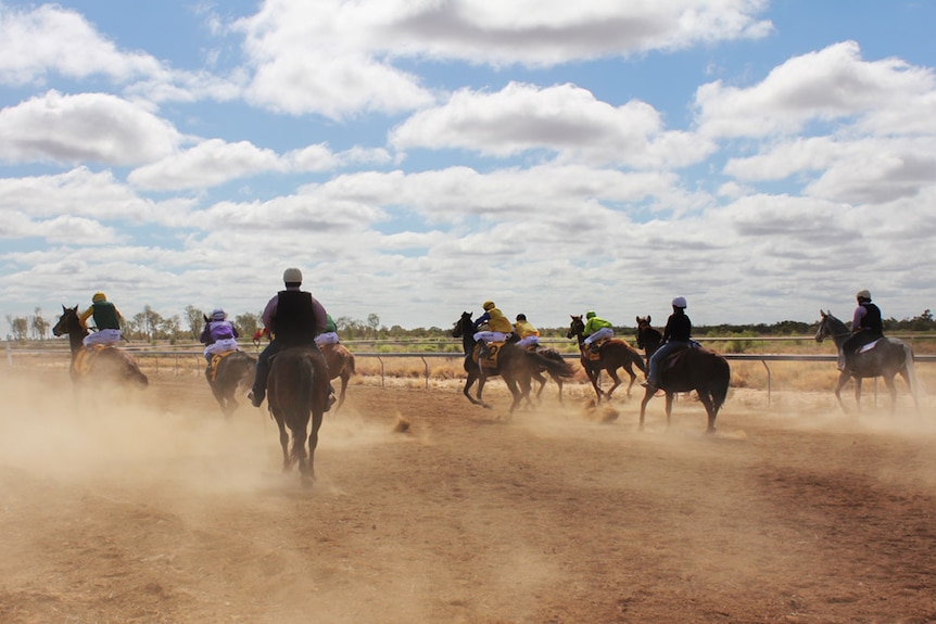 The horses take off, kicking up orange dust behind them.