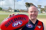 A man wearing a football jumper holding a colourful footy