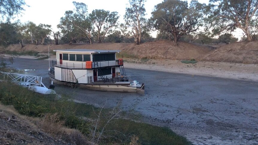 A boat sits stuck on a completely empty, dry river