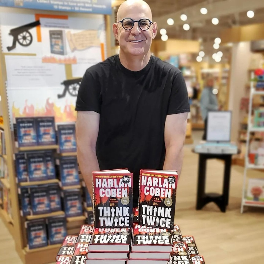 A photo of Harlan Coben standing behind several copies of his new book,Think Twice.