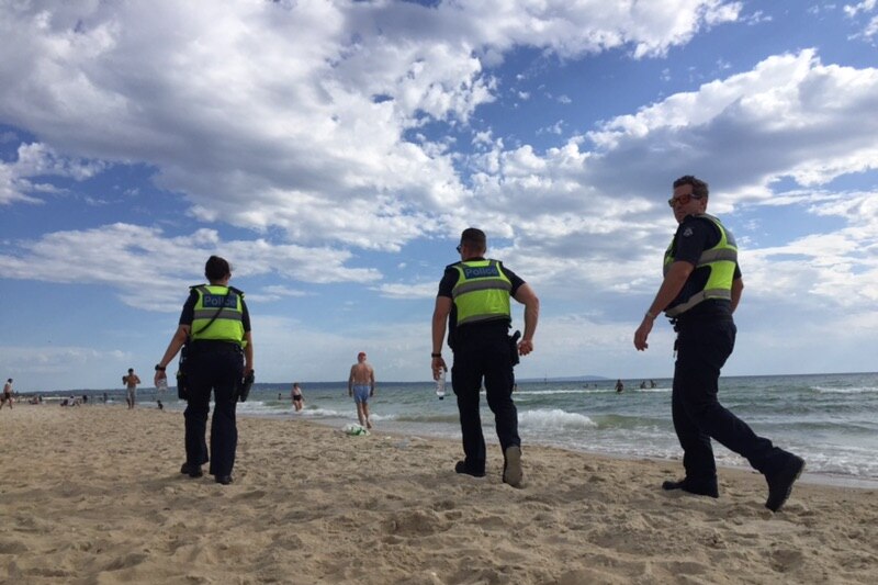 Three police officers are shown patrolling Chelsea beach.