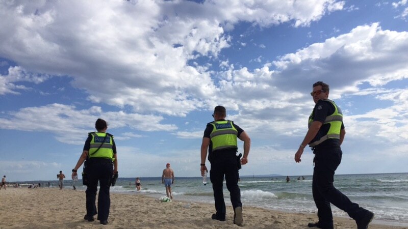 Three police officers are shown patrolling Chelsea beach.