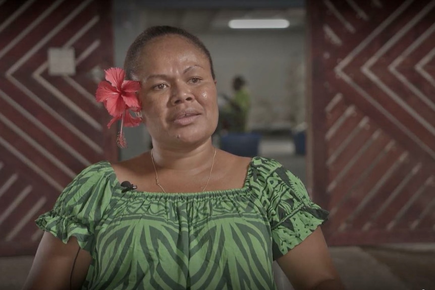 Head and shoulder shot of Julea King wearing green top and large red flower behind her right ear.