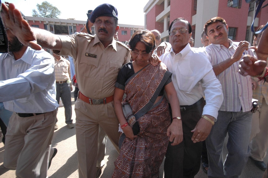 Police escort child welfare minister of Gujarat Maya Kodnani after she was arrested in Gandhinagar.