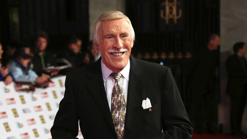Bruce Forsyth standing on a red carpet smiling.