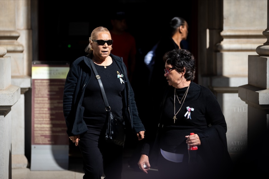 Two women wearing all black leave a court building