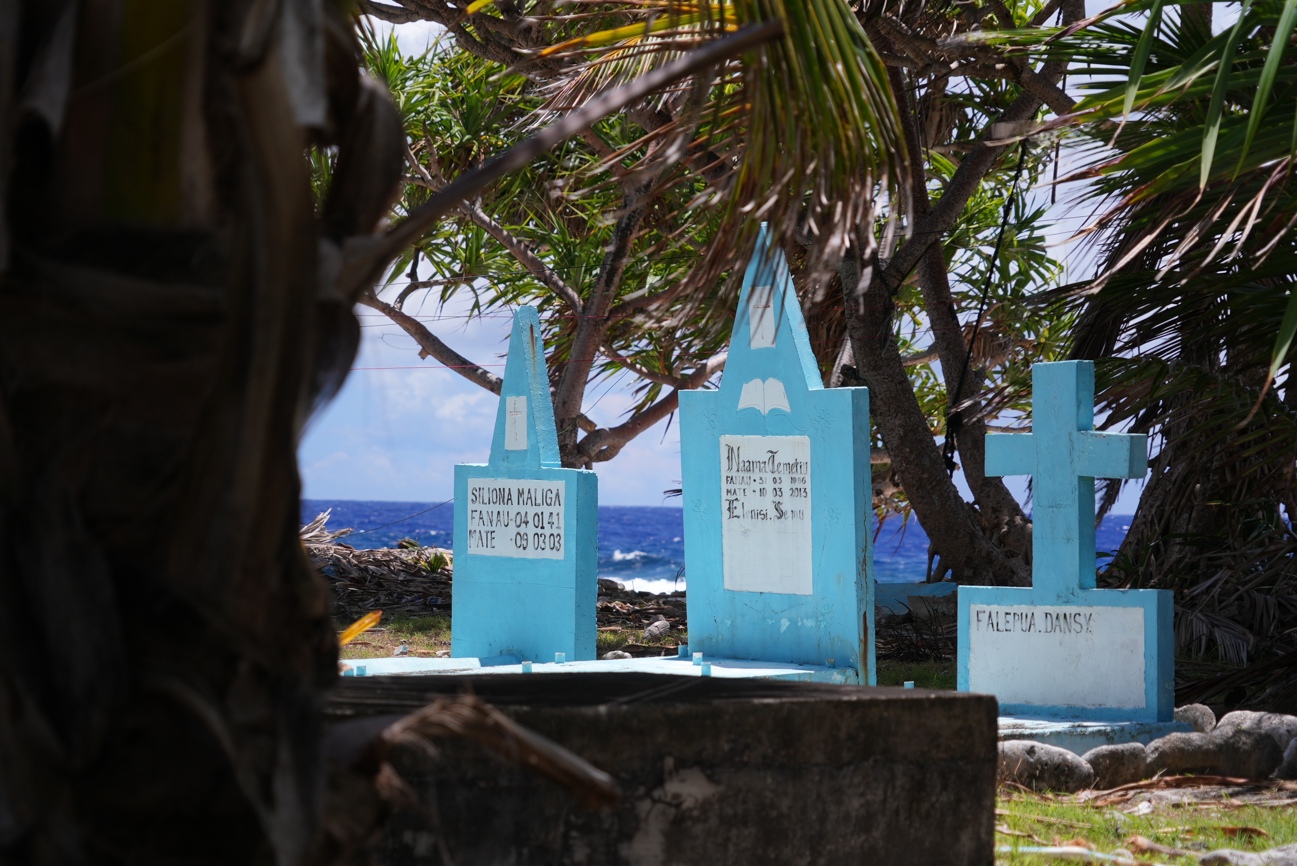 A photo of blue tombstones with a backdrop of the sea.