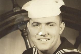 A black and white shot of a young man in a naval uniform.