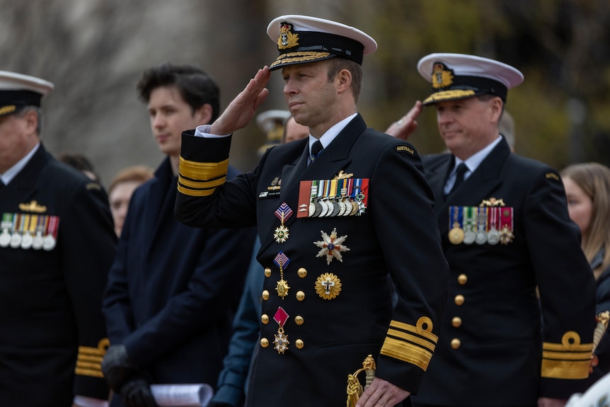 Michael Noonan in his naval uniform saluting