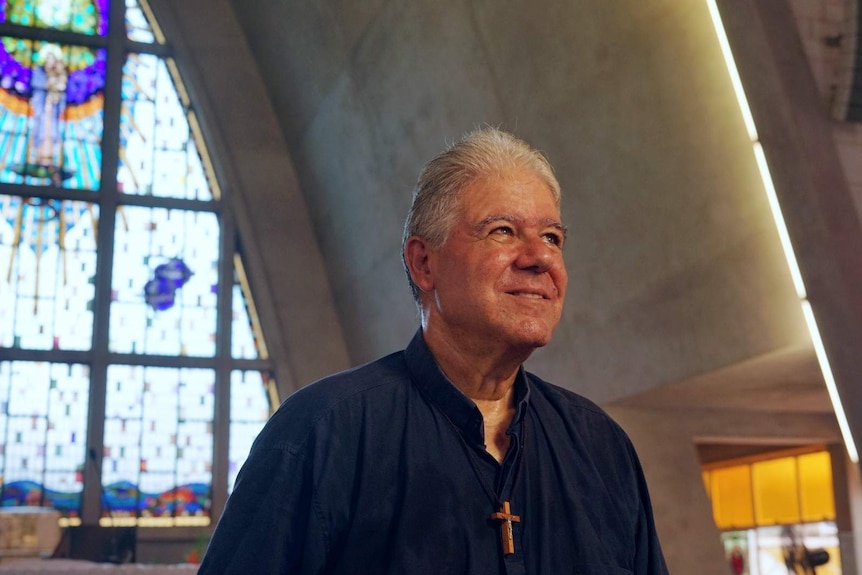 Bishop Charles Gauci smiles and looks off into the distance inside Darwin's St Mary's cathedral.