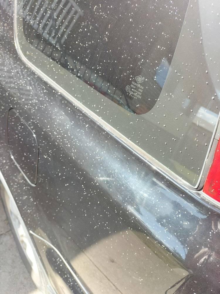 A dark close up shot of a car's paint job with white droplets