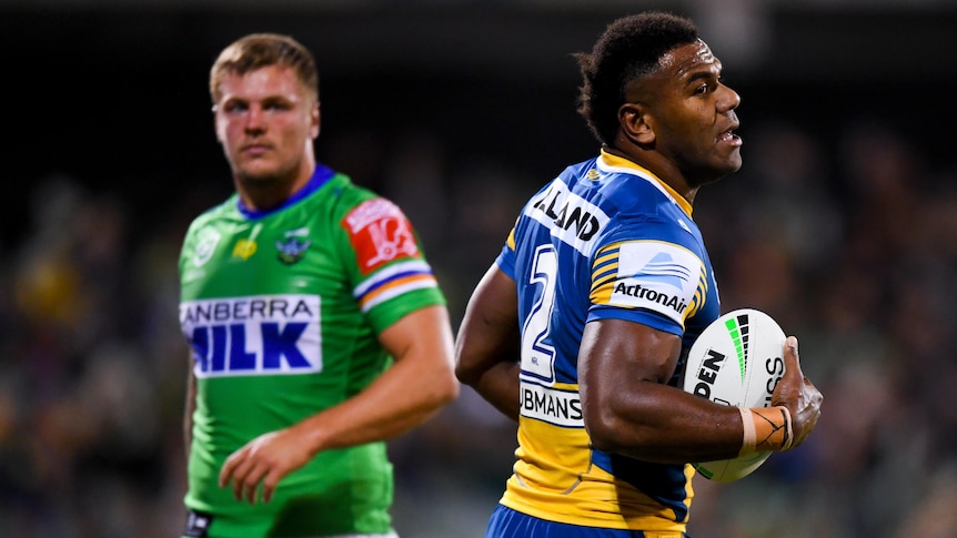 A Parramatta Eels NRL player holds the ball after scoring a try against the Raiders.