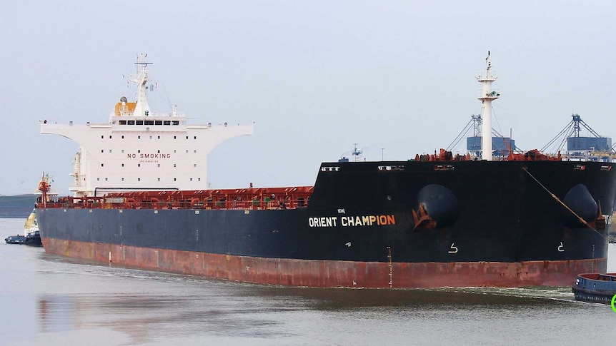 An large ship towed by a tug boat.