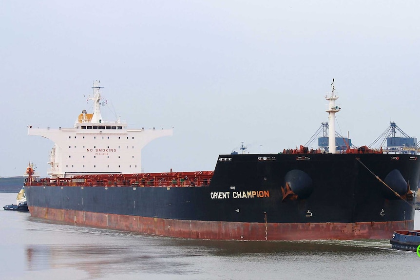 An large ship towed by a tug boat.