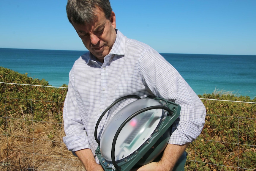 WA Fisheries Minister Dave Kelly demonstrates the SMART drum line technology that will be installed off Gracetown.