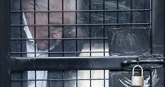Ron Medich is behind bars in the back of a police van.