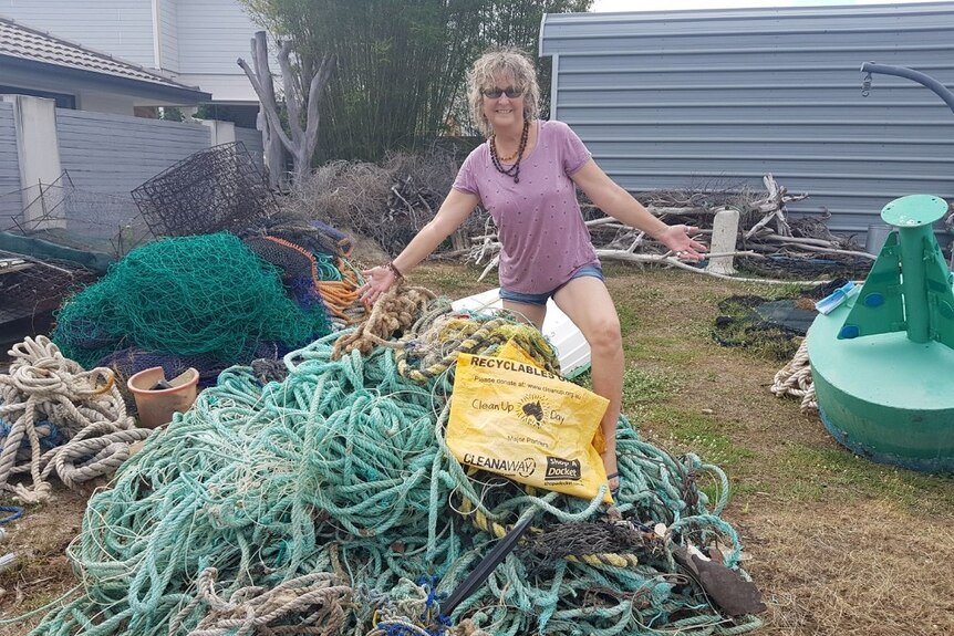Woman stands on top of a pile of fishing line, rope and other rubbish