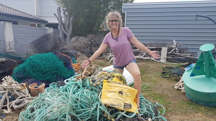 Woman stands on top of a pile of fishing line, rope and other rubbish