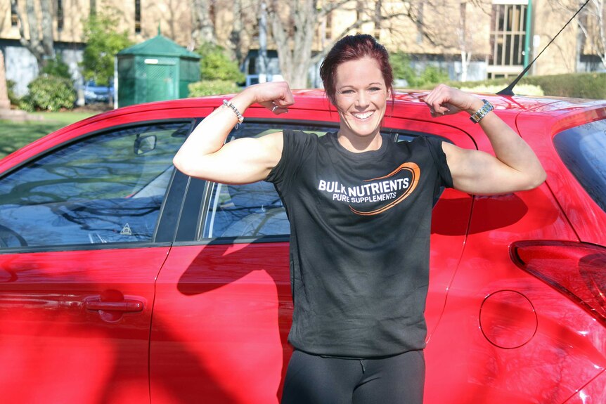 Casey Hill poses next to the car she just lifted