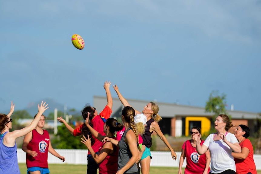 Women playing AFL, jumping up for a ball.