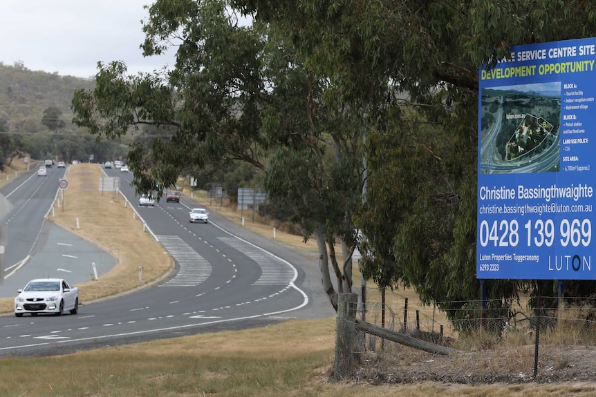 A sign for Rose Cottage with the Monaro Highway in the background.