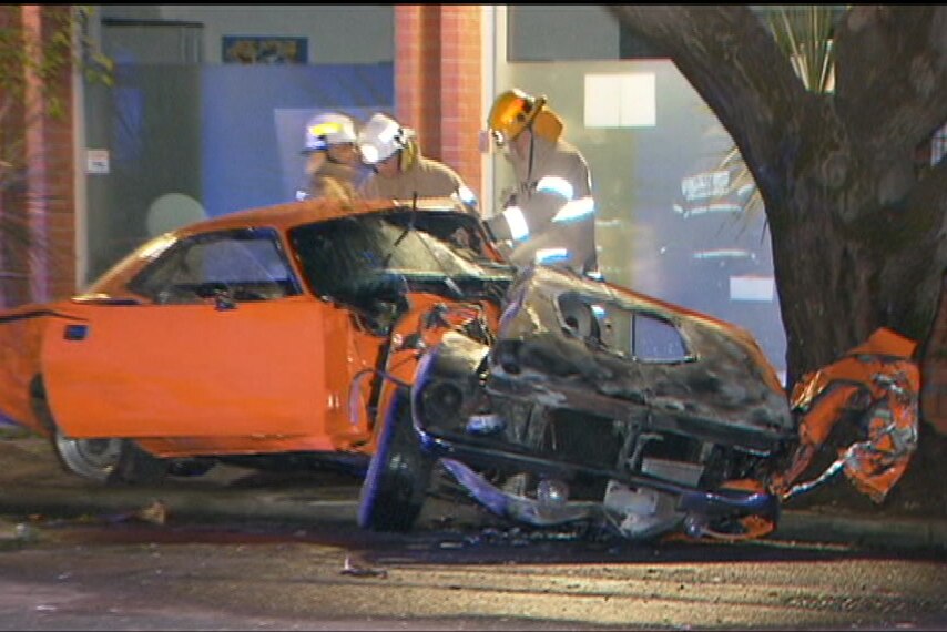 A damaged orange car which had hit a tree