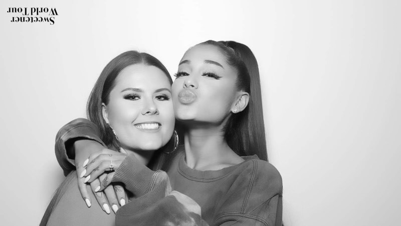 Black and white image of two girls embracing. One is smiling while the other is sending a kiss to the camera.