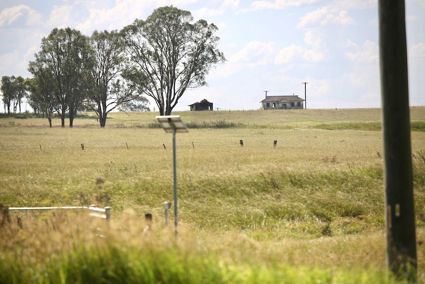 A picture of land with a house in the background