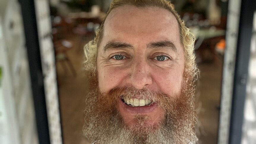 A close-up of a man with light coloured hair and long beard.
