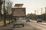An LED sign on the side of a road reading "COVID testing showground".