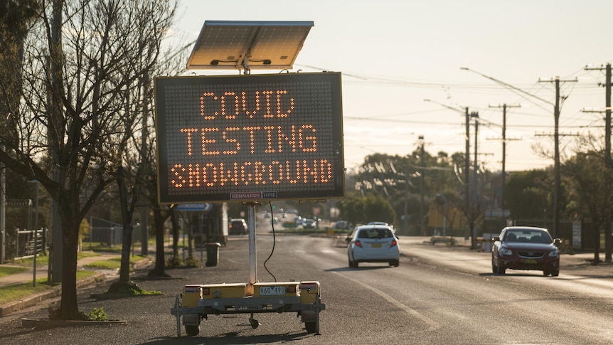 An LED sign on the side of a road reading "COVID testing showground".