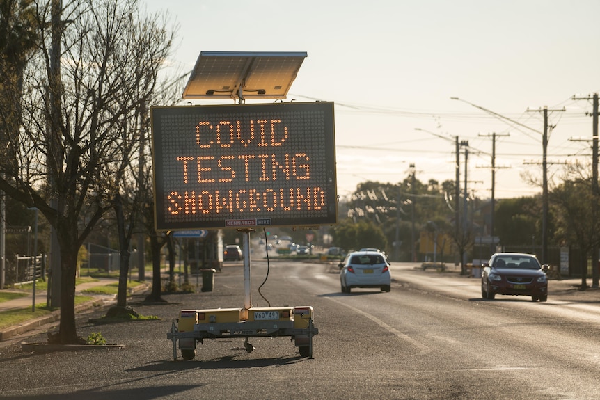 An LED sign on the side of a road reading "COVID testing showground".