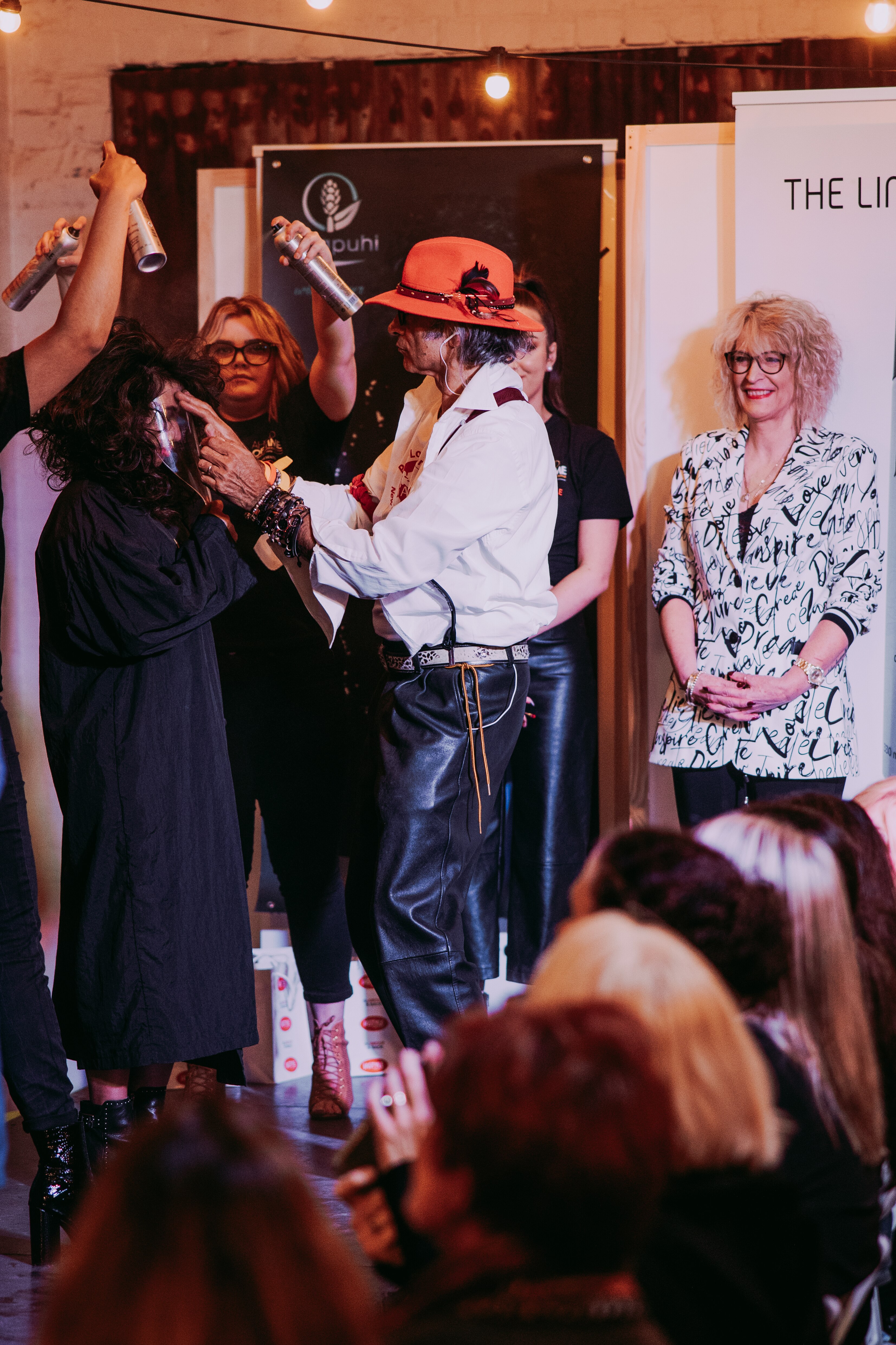 Hair and dress stylists working on a female model at a fashion show.   