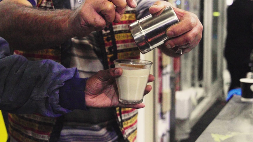 Man dusting cinnamon on top of a milky sahlab, photographed at the Ramadan night market in Lakemba, in Sydney's west.
