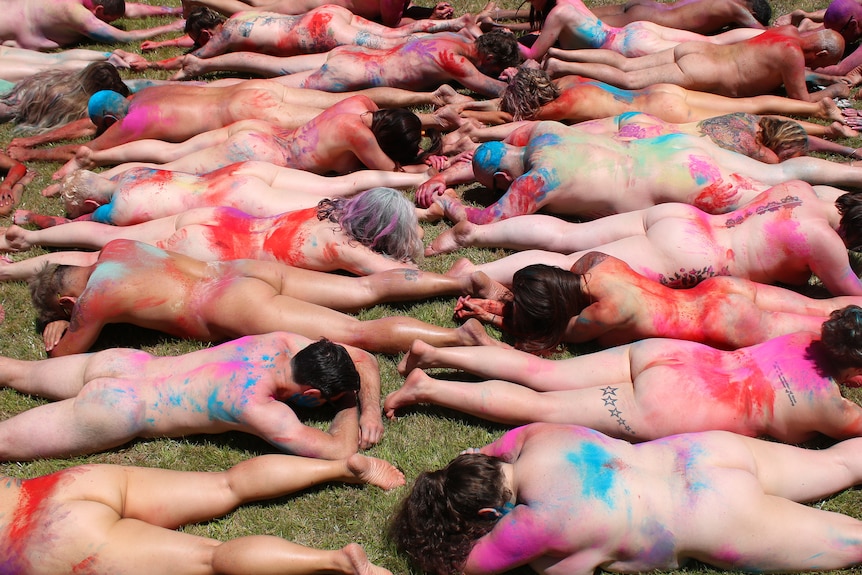 Rows of naked people with coloured dust all over them.