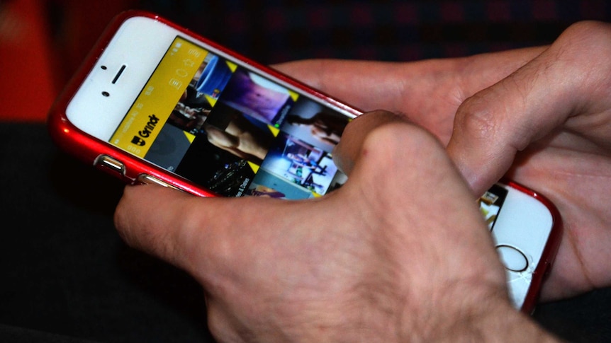 A person using a mobile phone with the Grindr app displayed