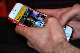 Hands hold a phone showing the Grindr app.
