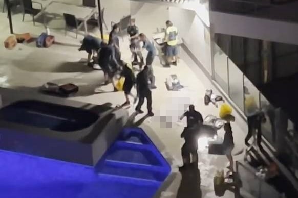 A distant shot of people at a medical emergency beside a pool at night.