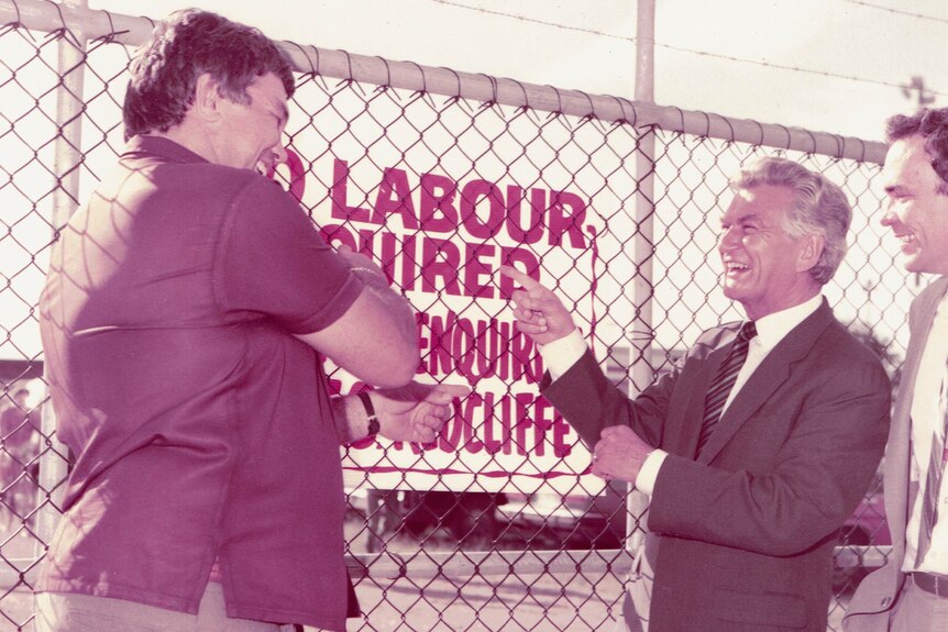 Former prime minister Bob Hawke laughs as he points to a 'labour hire' sign