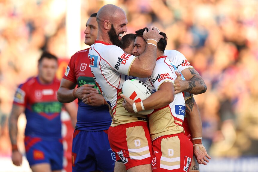 Three Dolphins NRL players embrace as they celebrate a try against the Knights.
