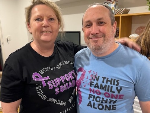 A man and a woman wearing pancreatic cancer fundraising t-shirts, smiling.