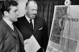 steinbeck and son, both in suits, look at a poster with text 'hire the handicapped', in black and white photo