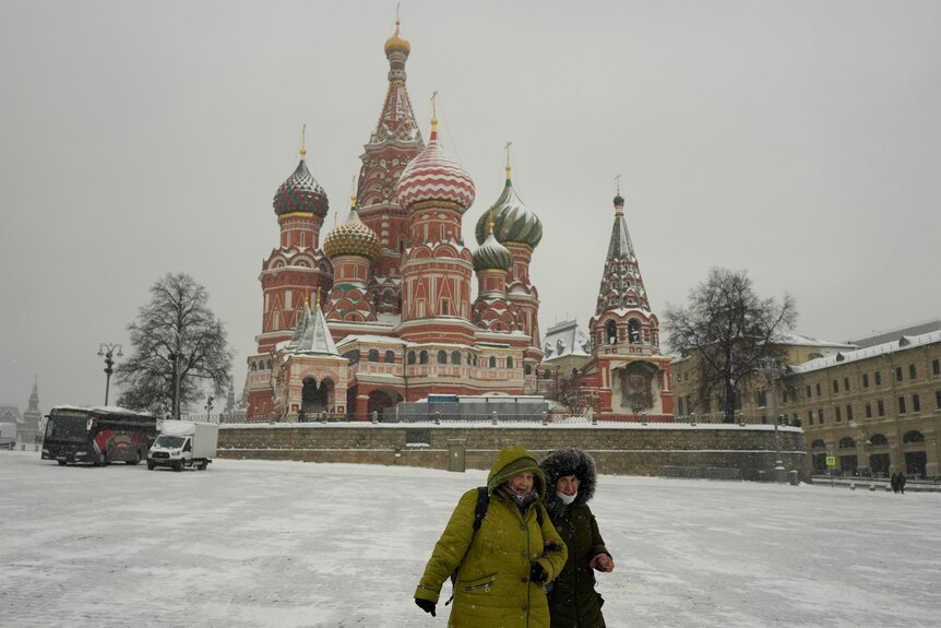 Women walk past the St Basil's Cathedral, in Moscow