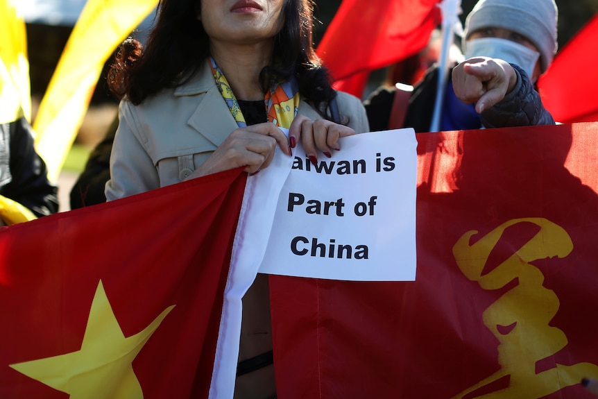 A woman holing Chinese national flag and a poster.