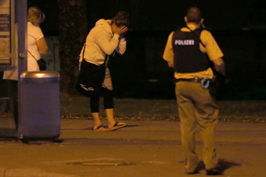 A woman covers her face after a shooting rampage at the Olympia shopping mall in Munich, Germany.