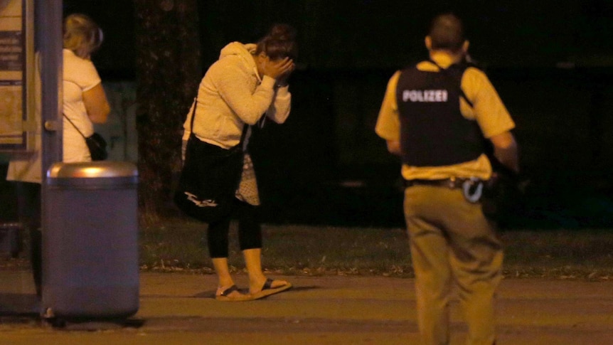 A woman covers her face after a shooting rampage at the Olympia shopping mall in Munich, Germany.